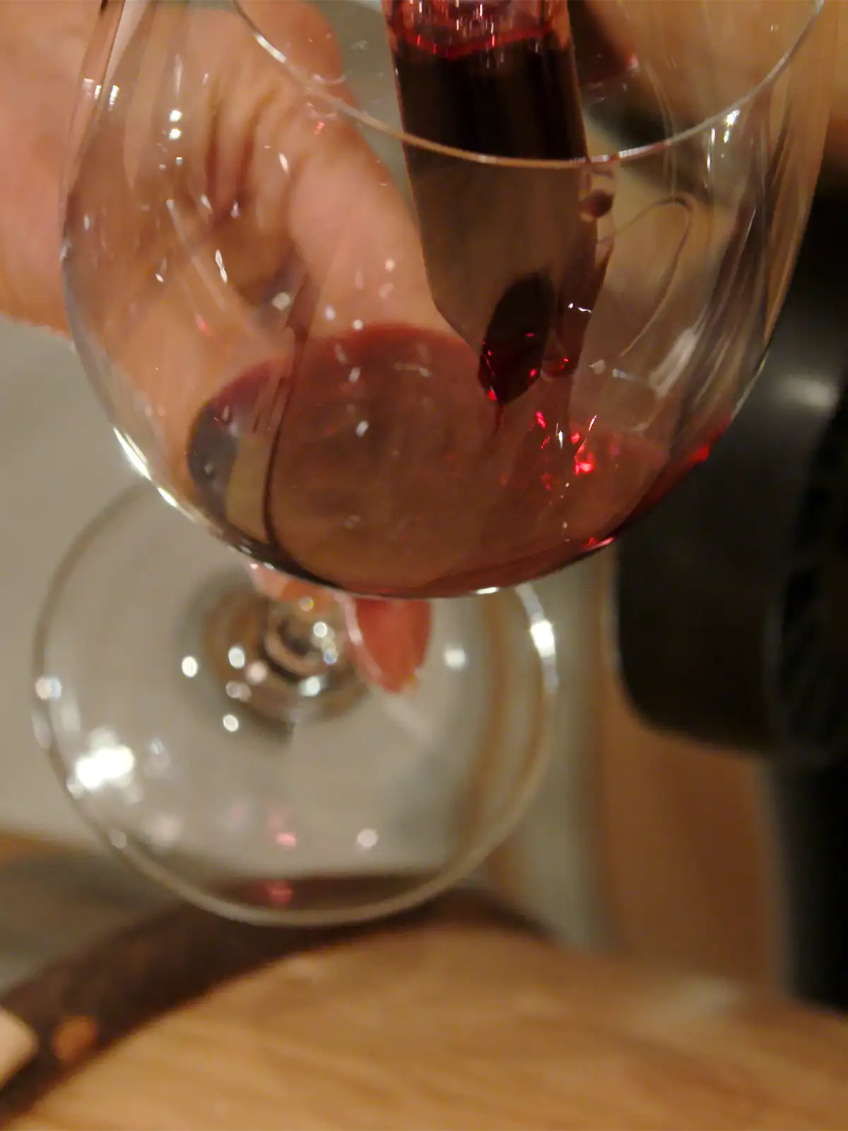 Red wine being poured into a large glass.