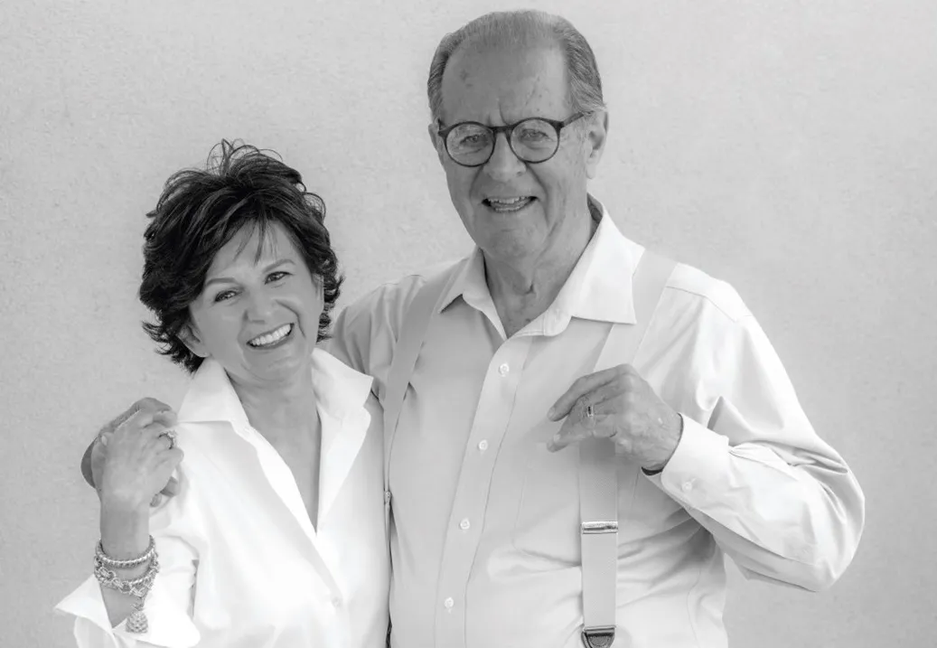 An older man and woman posing together and smiling.