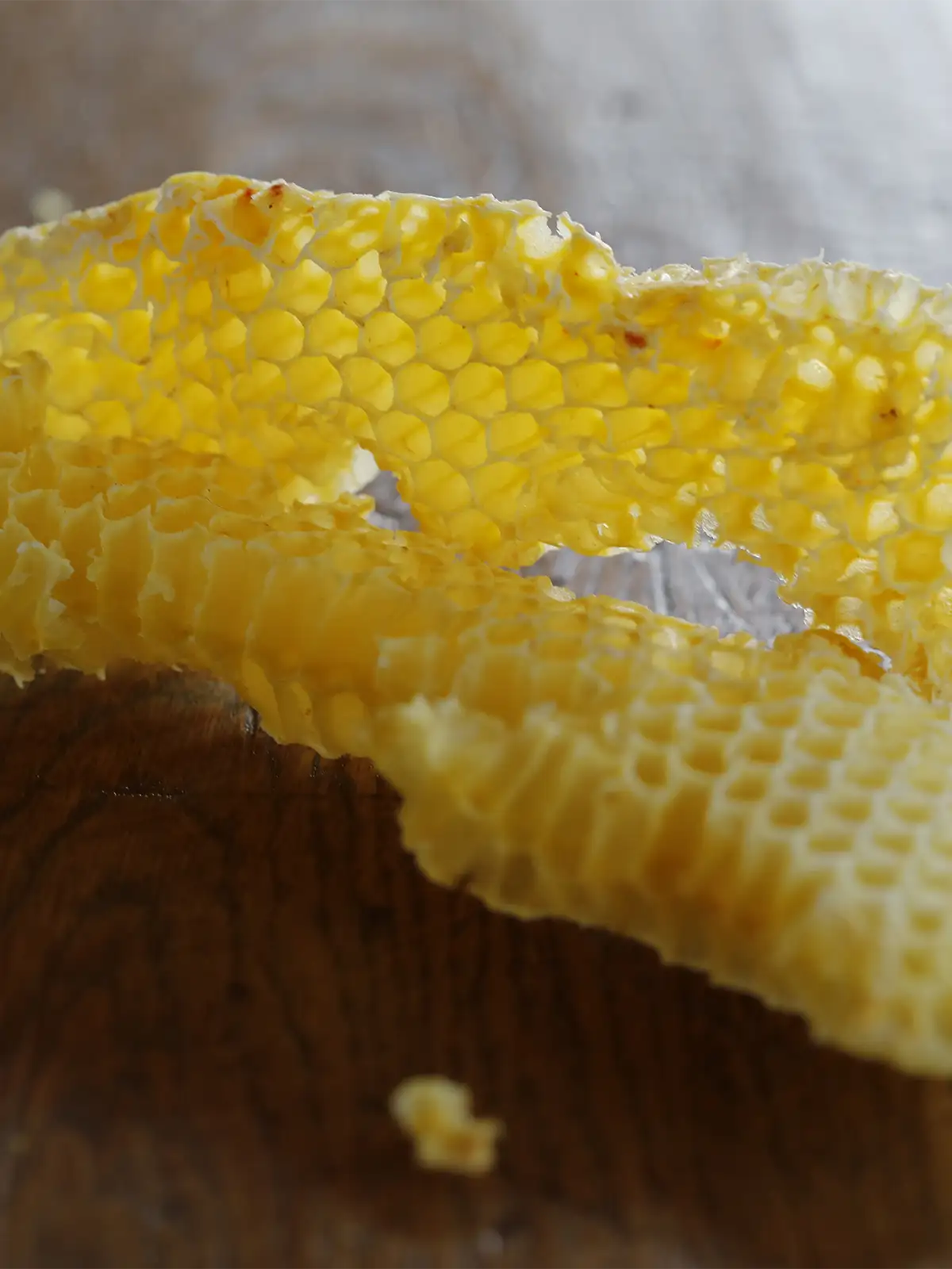 A piece of yellow beeswax honeycomb on a wooden surface.